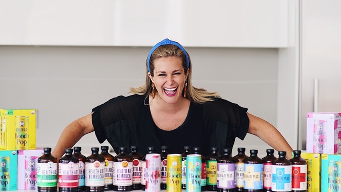 Daina Trout, co-founder of Health-Ade Kombucha. Standing with a line of Health-Ade products.