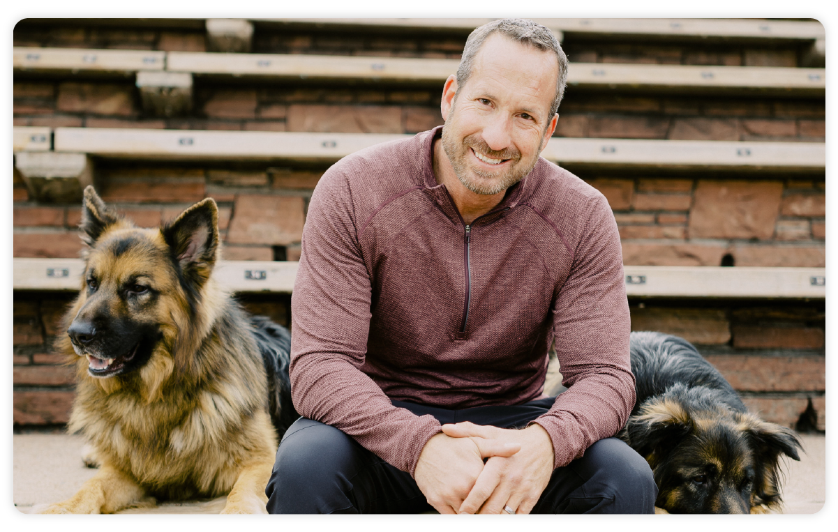 Adam Cantos, CEO of RE/MAX - sitting on steps with dogs