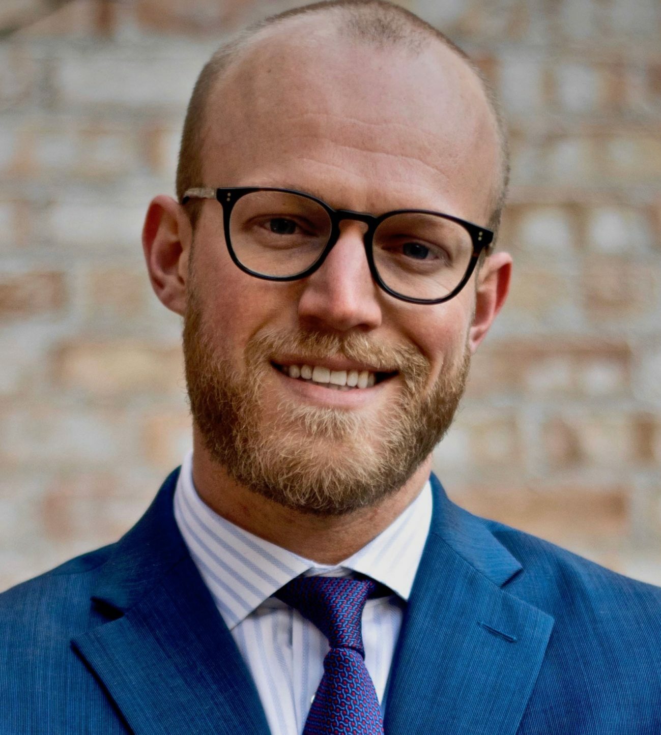 A man with glasses smiling.