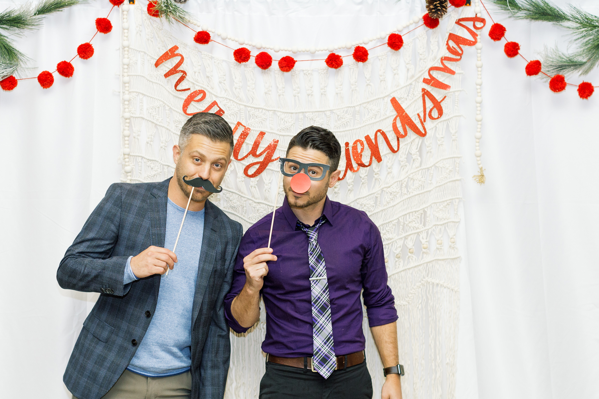 A man posing with a fake mustache while another man poses with a fake pair of glasses.