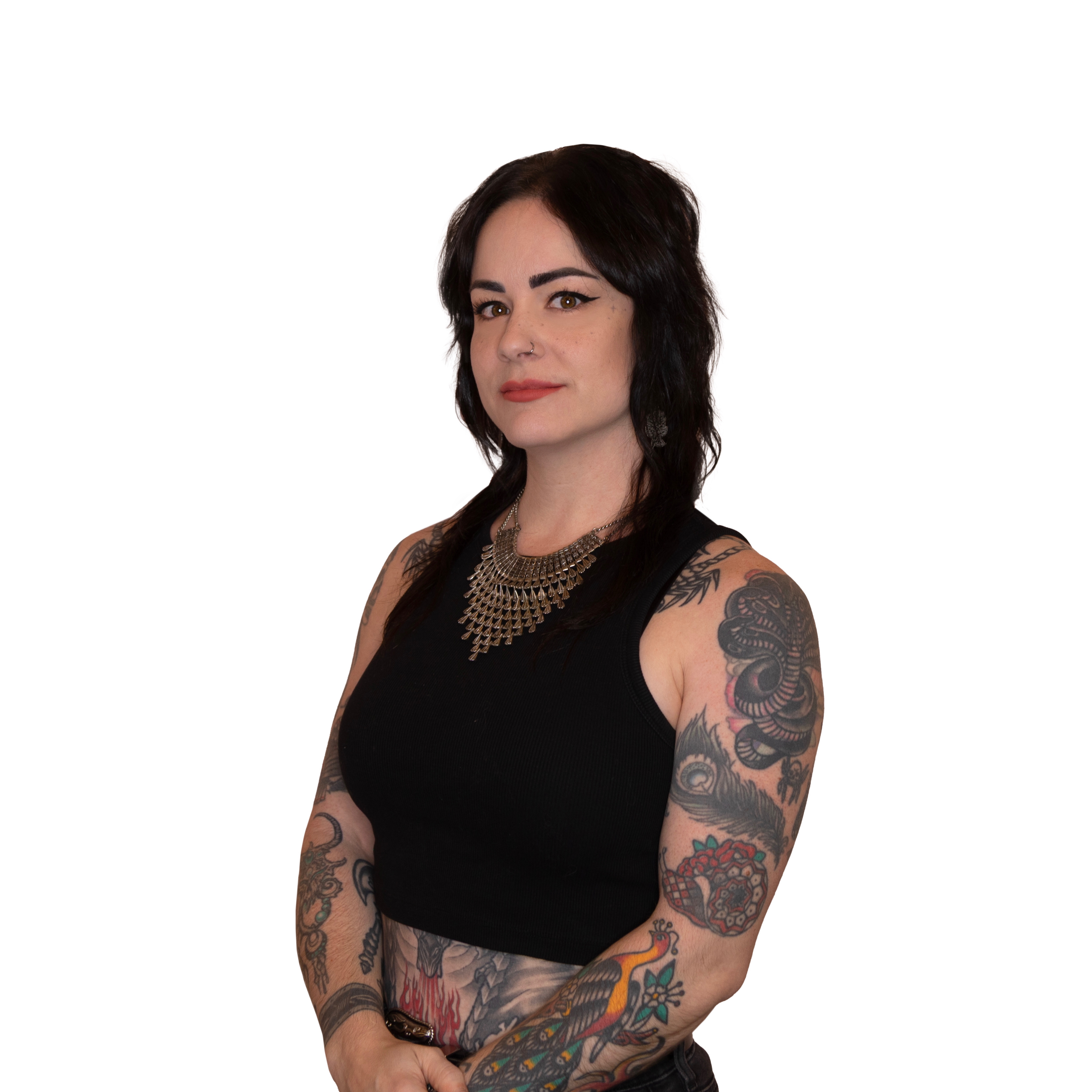 Woman with dark hair, wearing a black sleeveless top and intricate necklace, showing colorful tattoos on her arms and midriff.