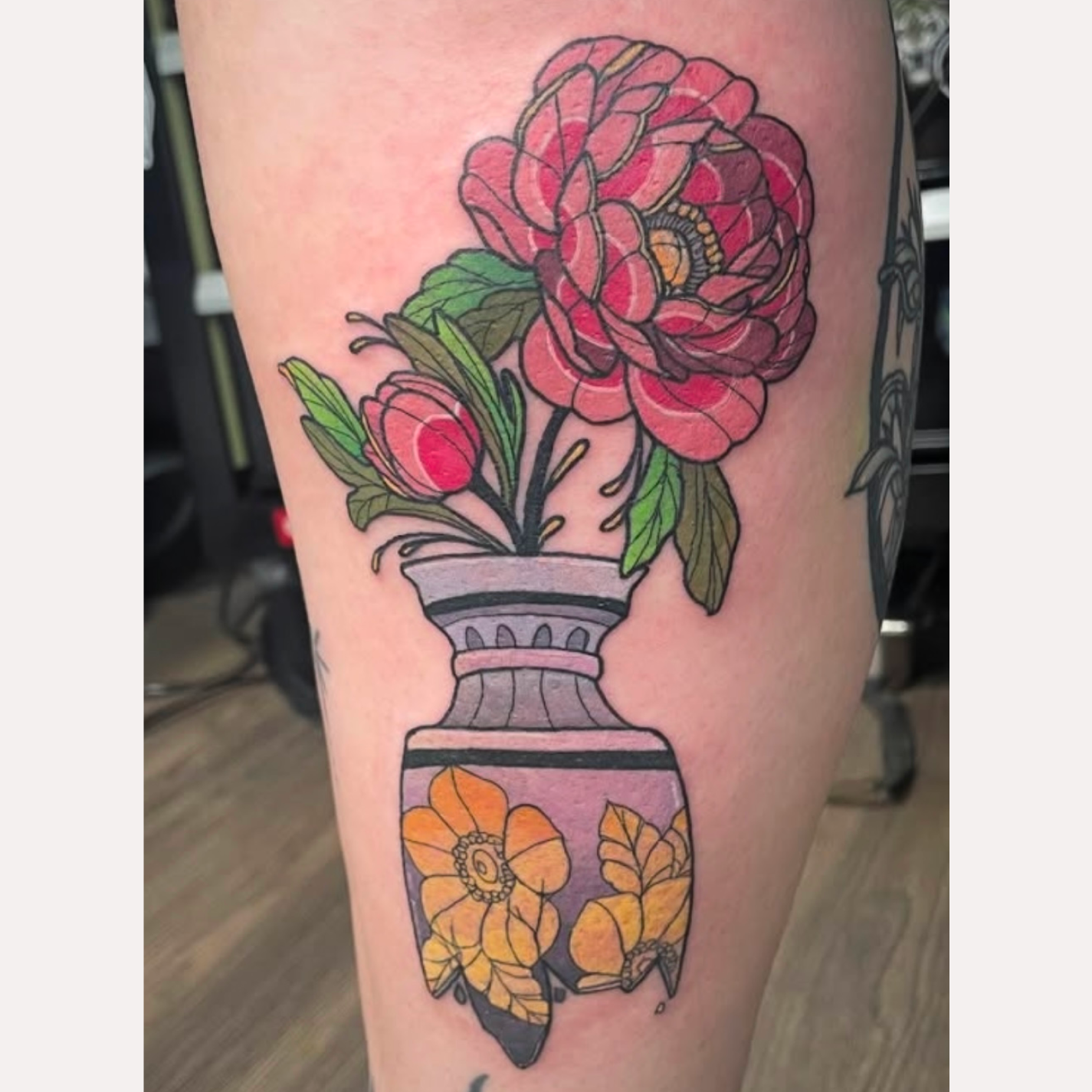 Tattoo of a pink flower with green leaves in a purple vase decorated with yellow flowers on a person's skin.