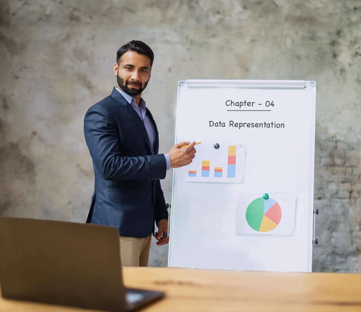 Man in a blazer pointing to a whiteboard with charts and text 'Chapter - 04 Data Representation' during a presentation.