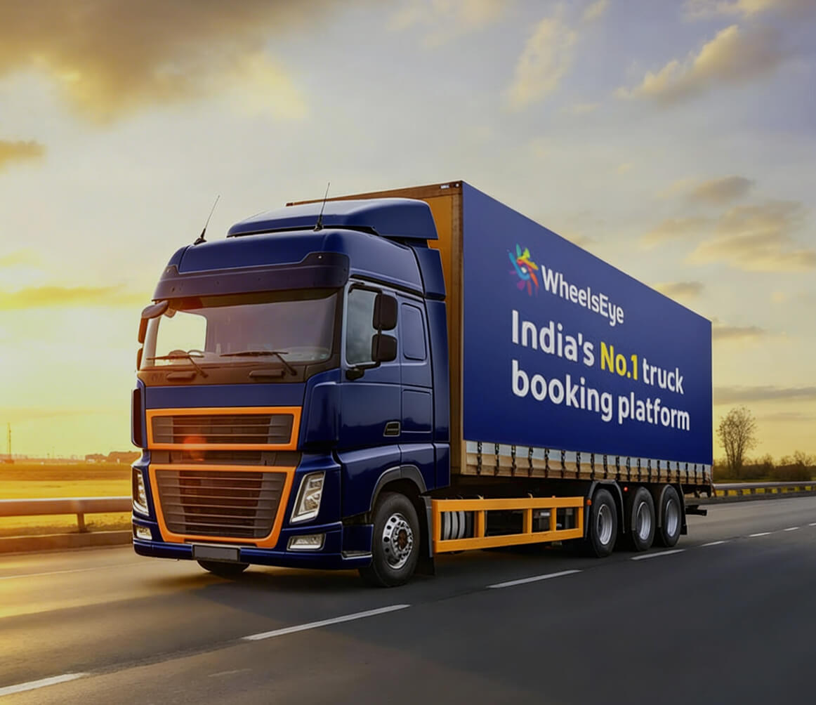 Blue and orange truck driving on a highway at sunset with a banner stating WheelsEye India's No.1 truck booking platform.