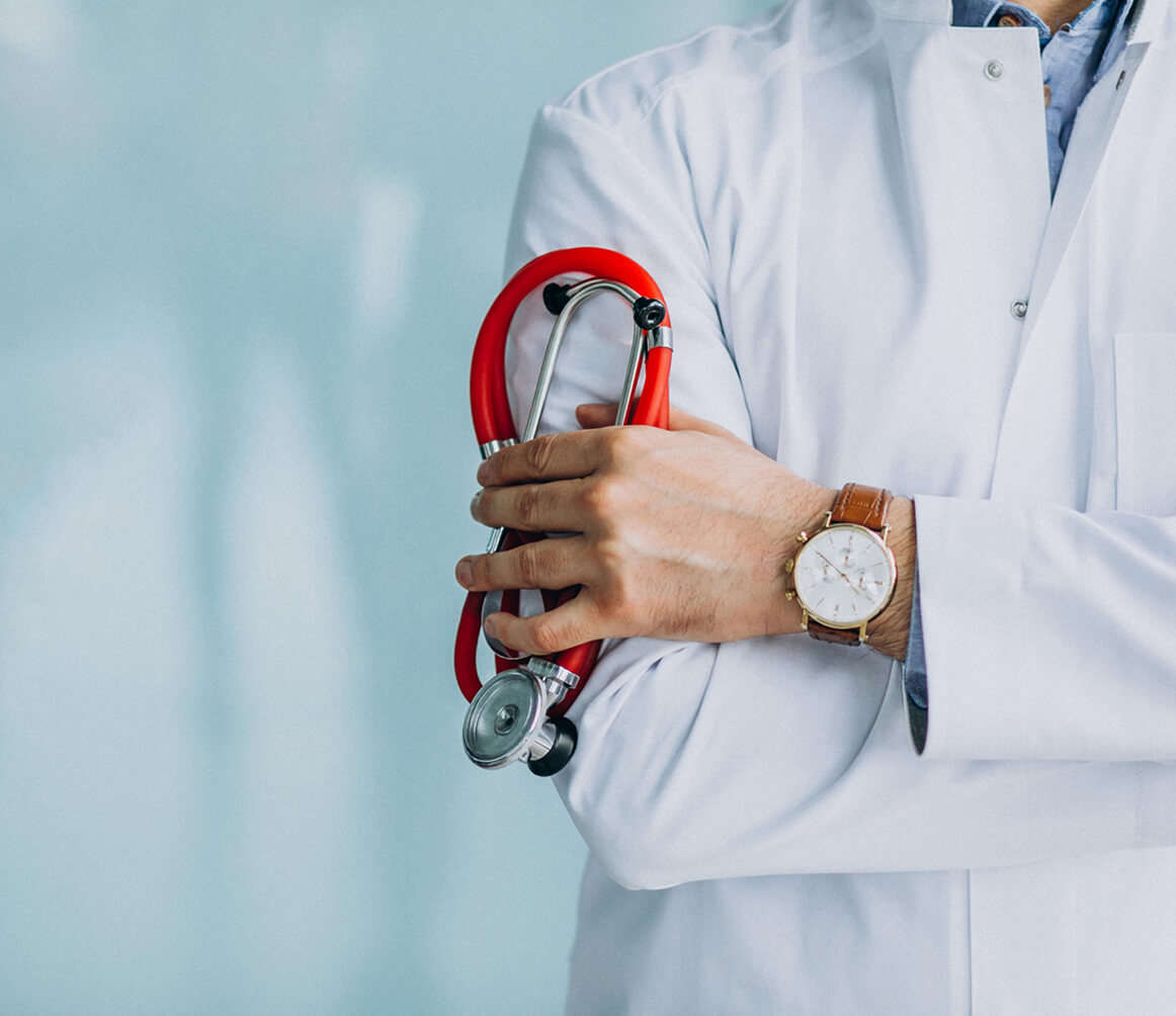 Doctor in white coat holding a red stethoscope with arms crossed.