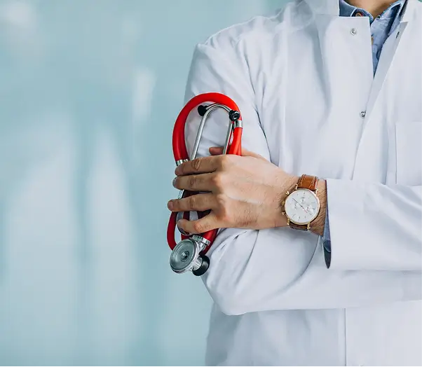 Doctor in white coat holding a red stethoscope with arms crossed.