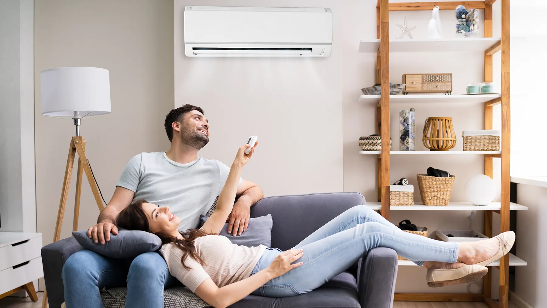 Couple relaxing on a couch with a wall-mounted split system air conditioner installed above them in a living room in Port Macquarie