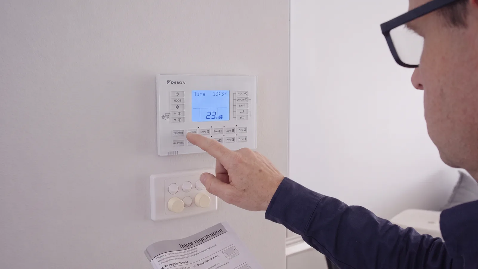 A Renew Air Technician configuring a Daikin ducted air conditioning zone controller on a wall during installation in Port Macquarie