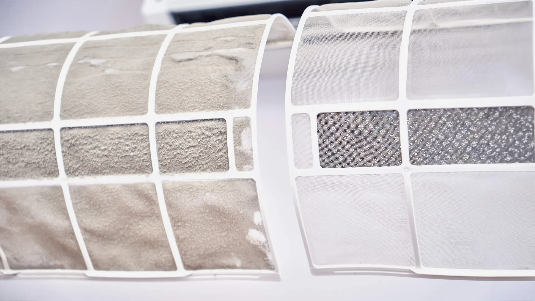 Dirty air conditioning filter next to a clean filter showing dust and debris build-up