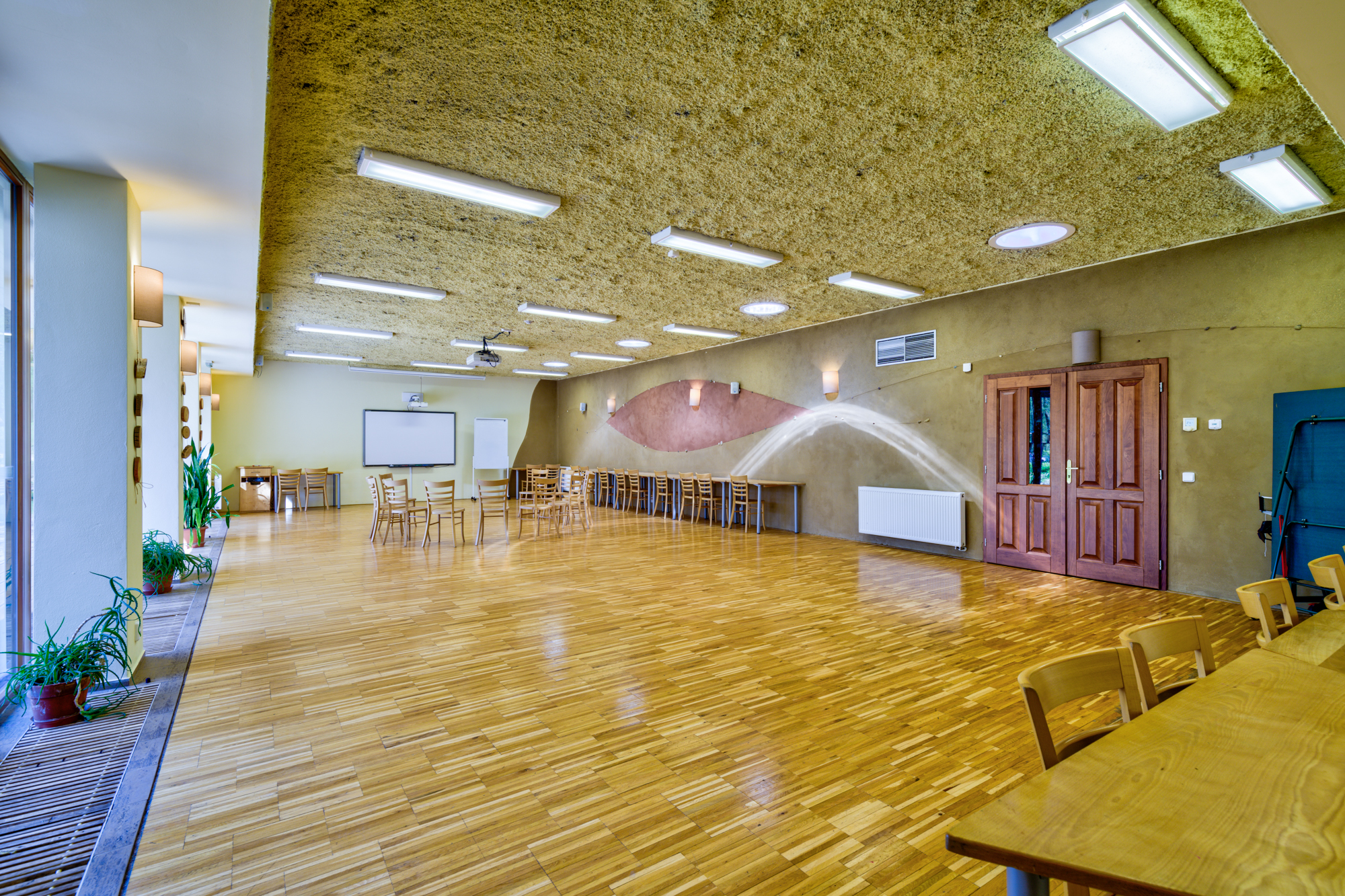 sál s promítacím plátnem a stoly se židlemi