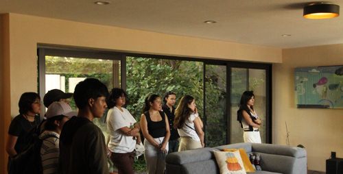 Personas paradas delante de un cancel de aluminio que da hacia un patio escuchando una explicación