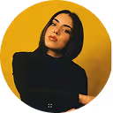 A woman with her arms crossed in front of a yellow circle.