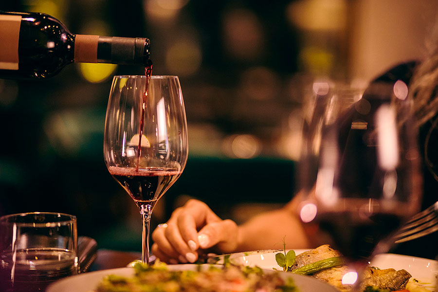 Glass of red wine being poured at a restaurant.