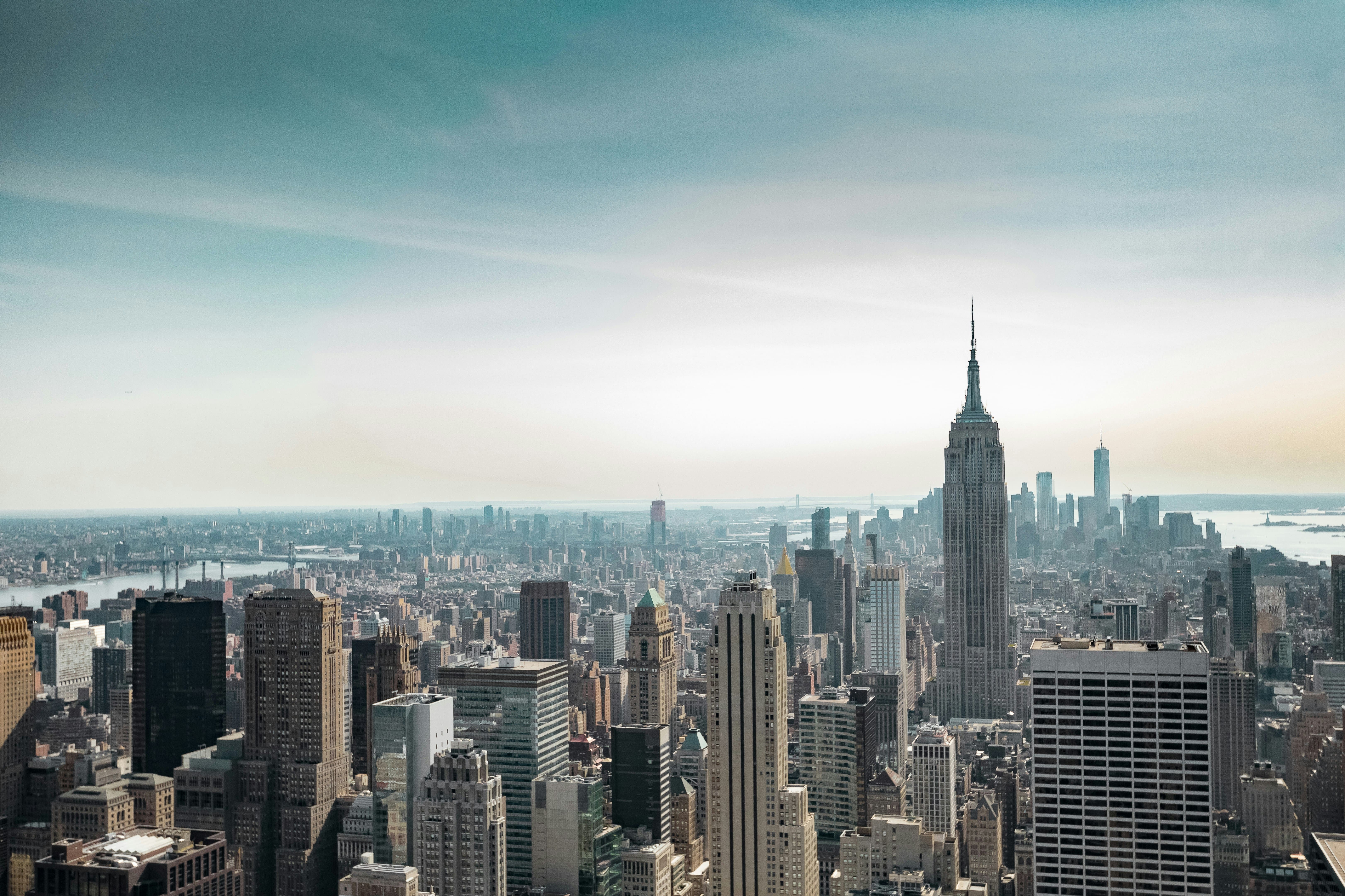 Aerial view of New York City skyline with the Empire State Building prominent among other skyscrapers under a partly cloudy sky