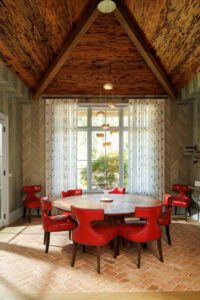 The dining room's modern leather chairs add a vibrant pop to the rustic floors and wood accents.