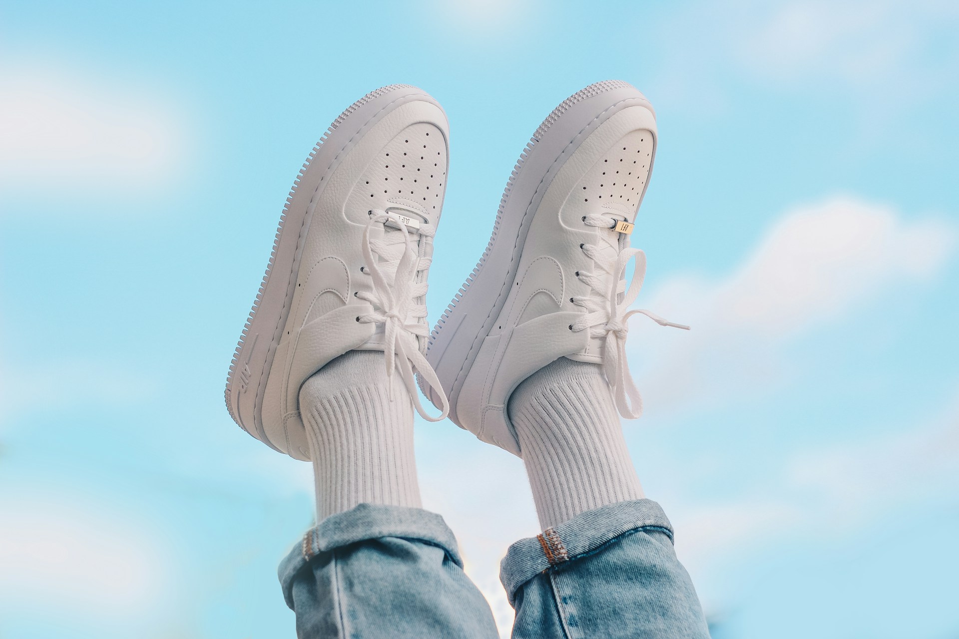 White Nike Air Force 1 on a person's feet against a blue background