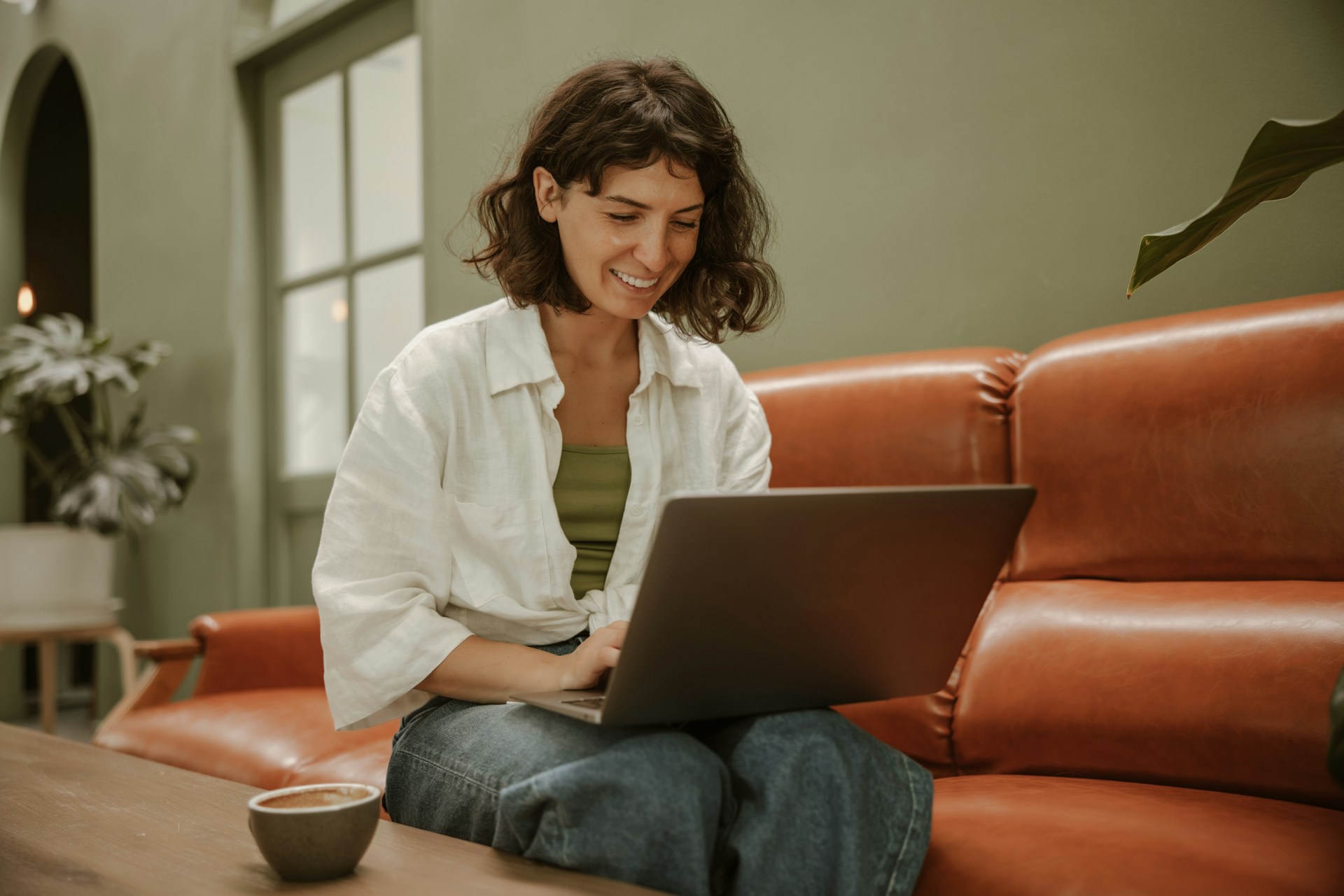 A girl drinking coffee and using a laptop