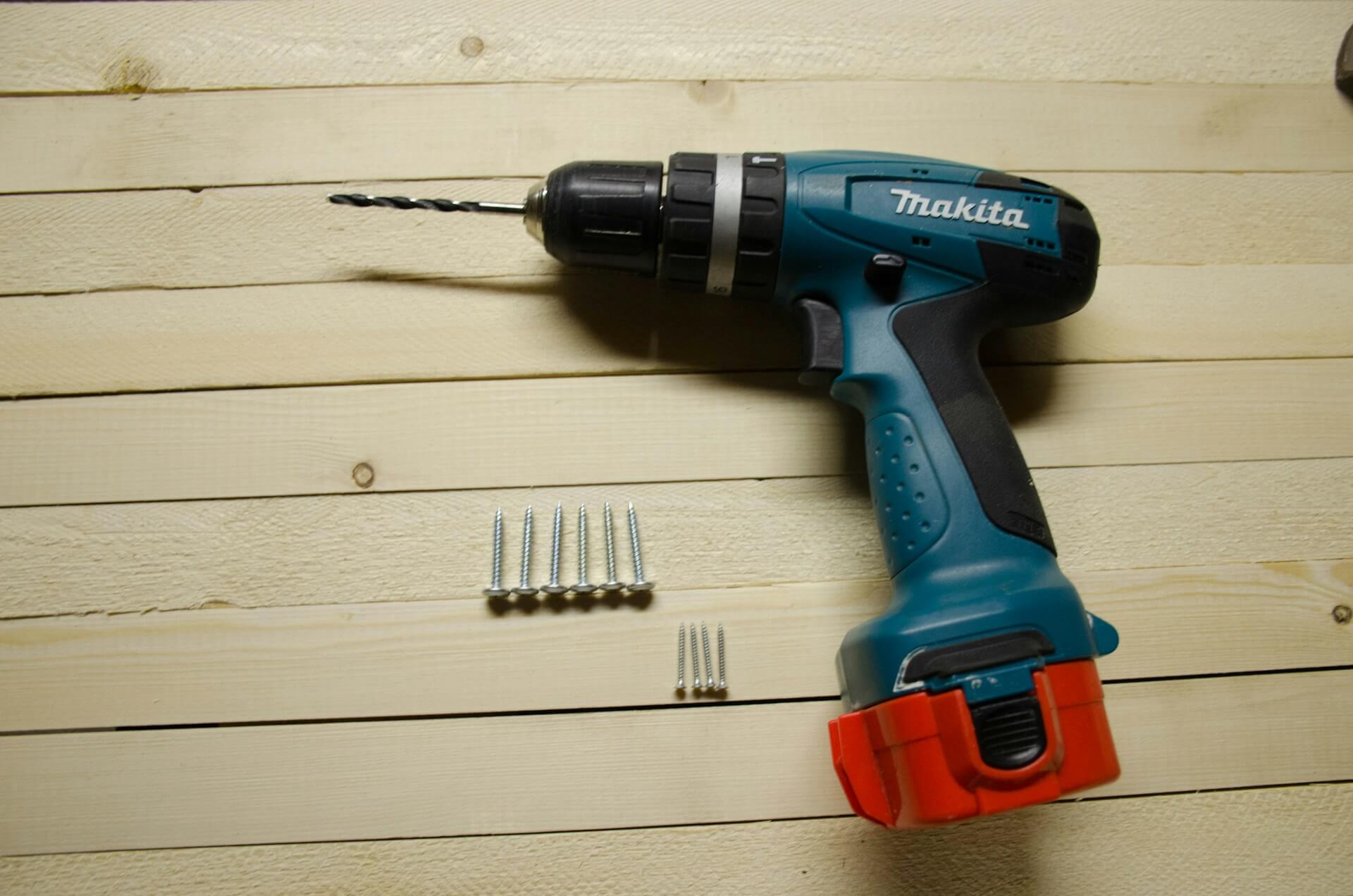 A blue and red drill on a wooden floor