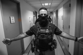A masked federal agent in an immigration court hallway in New York, shown in the PSR Memphis commentary