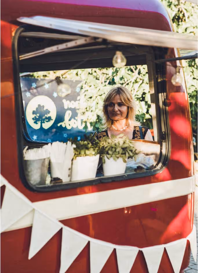 Mujer esperando a ser atendida en el food truck rojo durante Noches del Botánico.