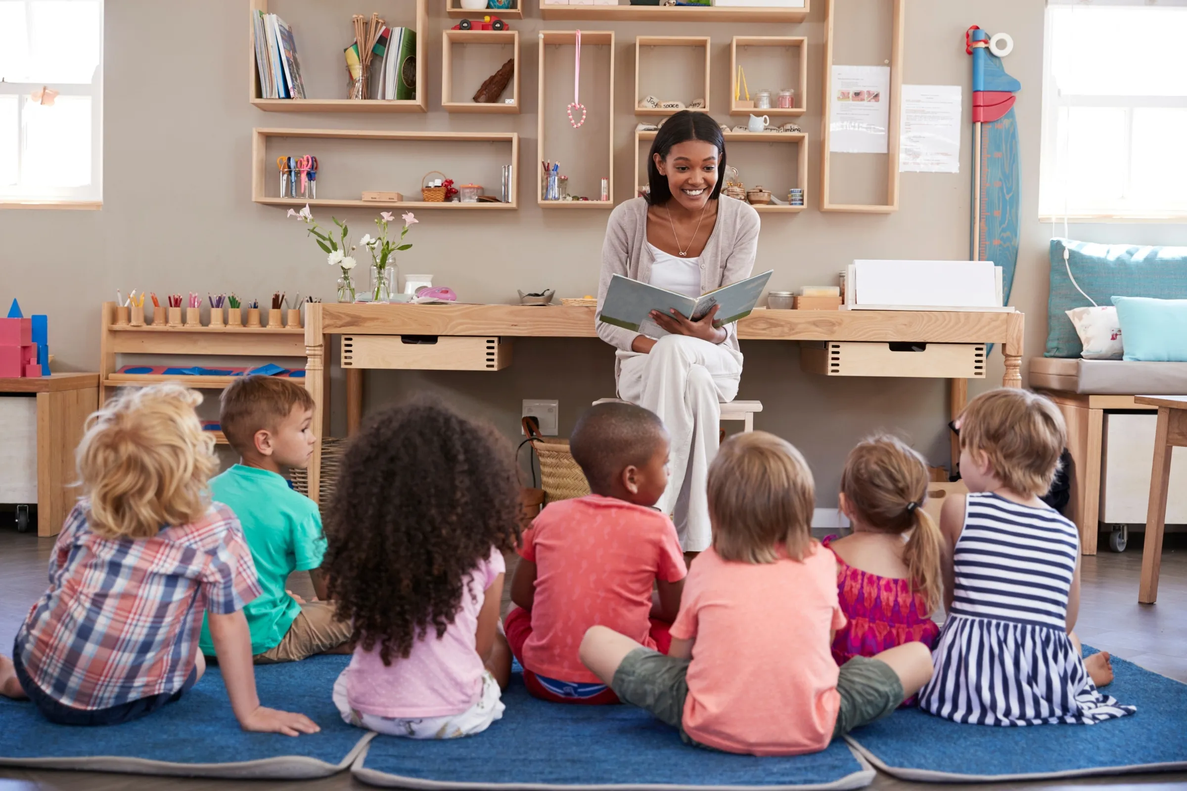 A woman reads a book to a group of children. - New Leaders Images