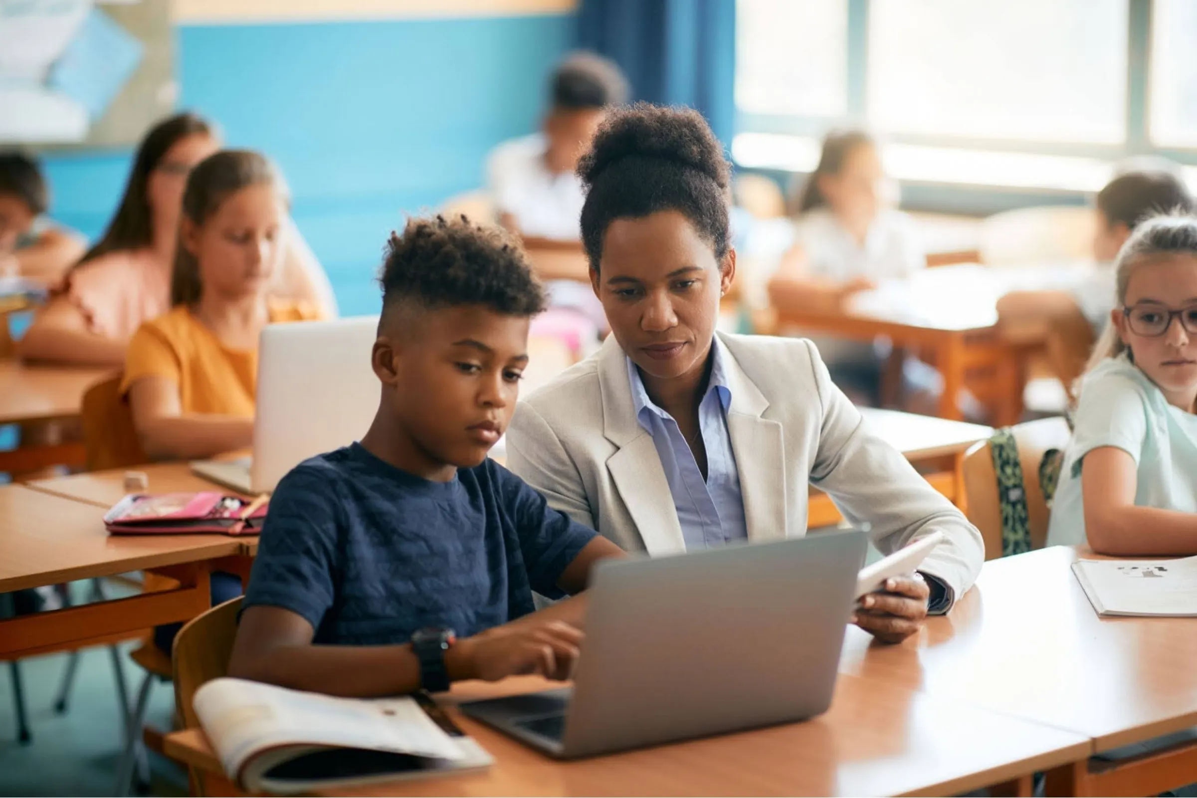 A woman and a boy are sitting at a table with a laptop. - New Leaders Images