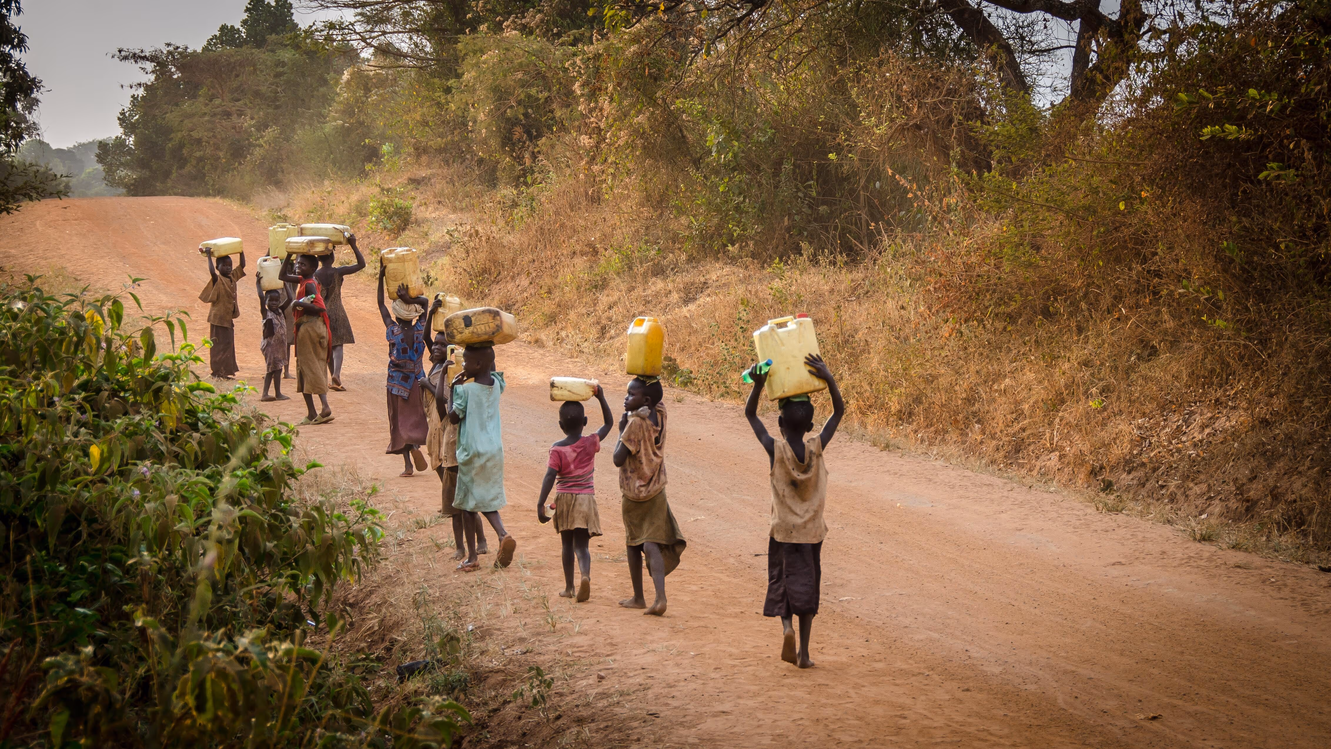 African children walking carrying water jugs on their heads