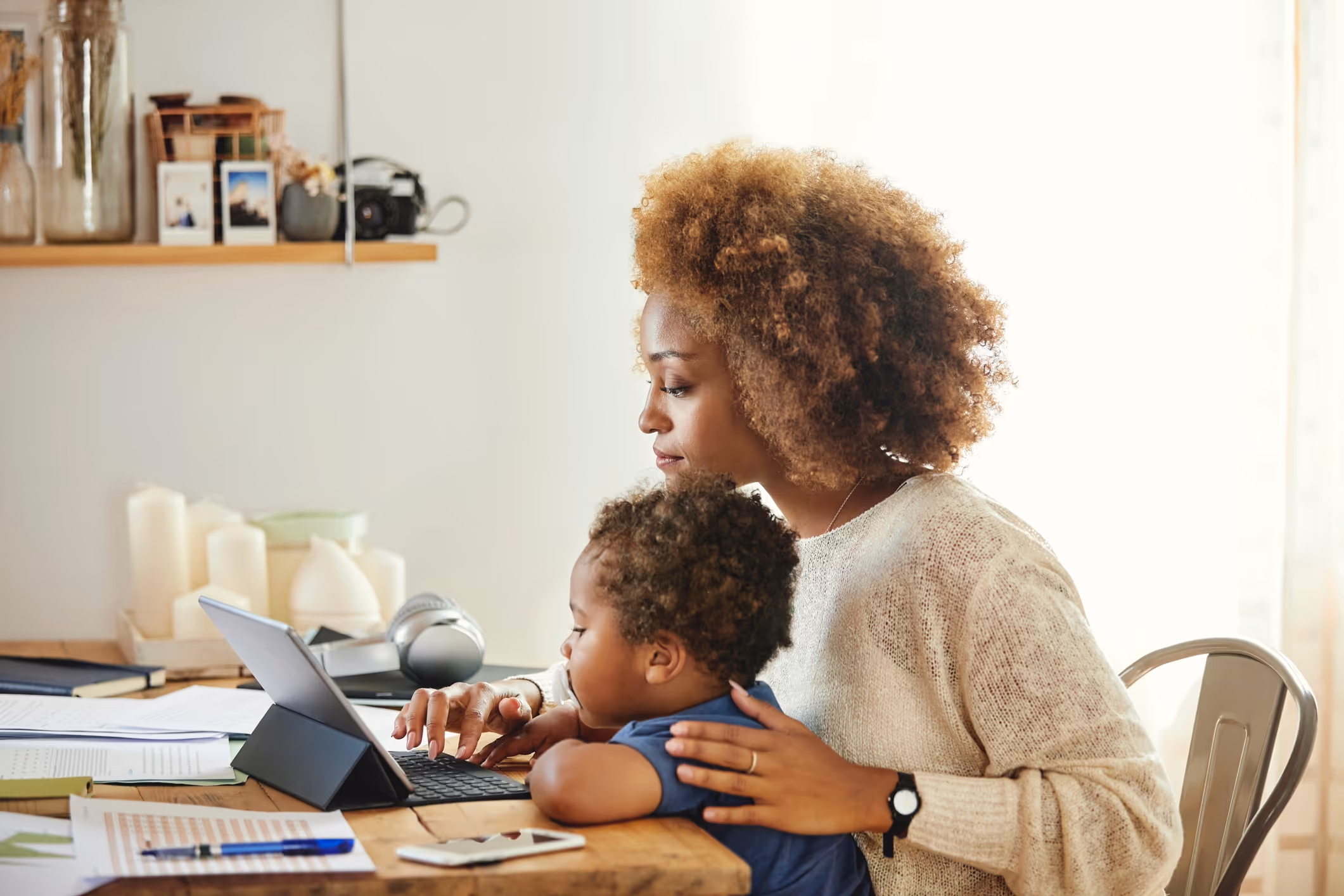 Single mother holding her child while working on a laptop
