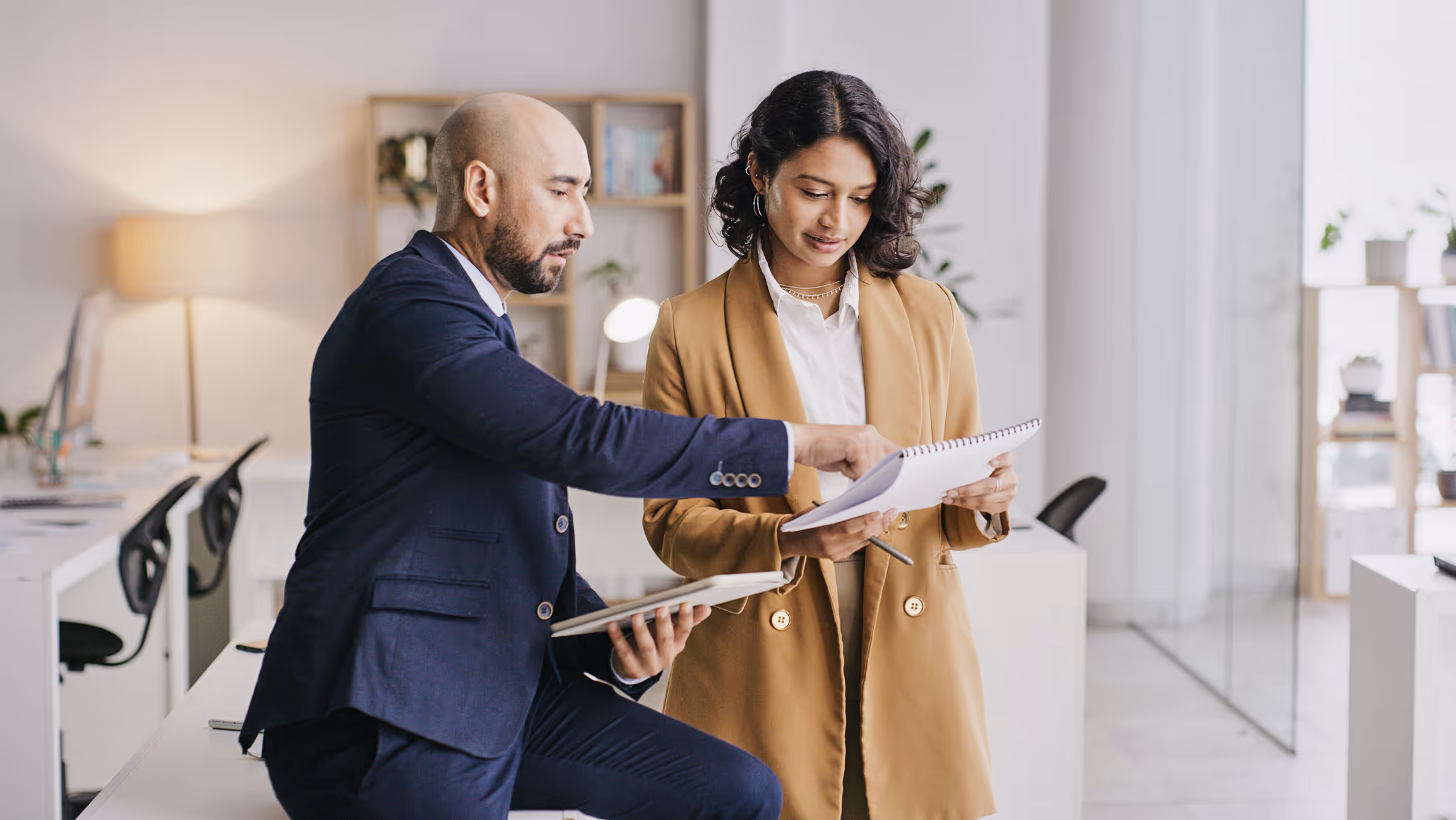 Woman and man standing side by side, man pointing to paper woman is holding