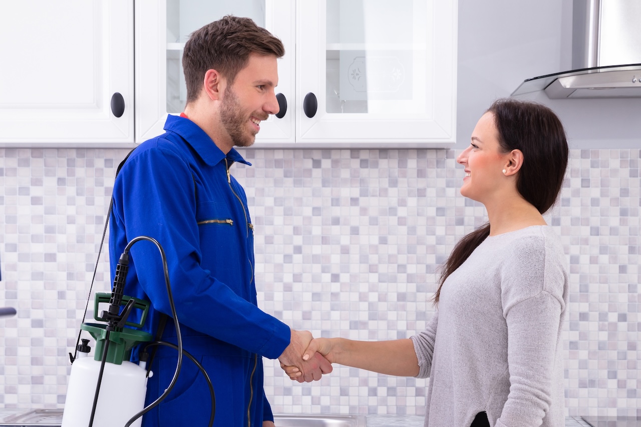 Pest control worker shaking hands with a female client outside her home, symbolizing trust, professionalism, and customer service.