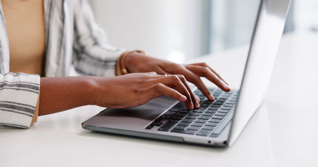 Woman typing a pest control price increase notice on a laptop, drafting a professional email to inform customers about service changes.