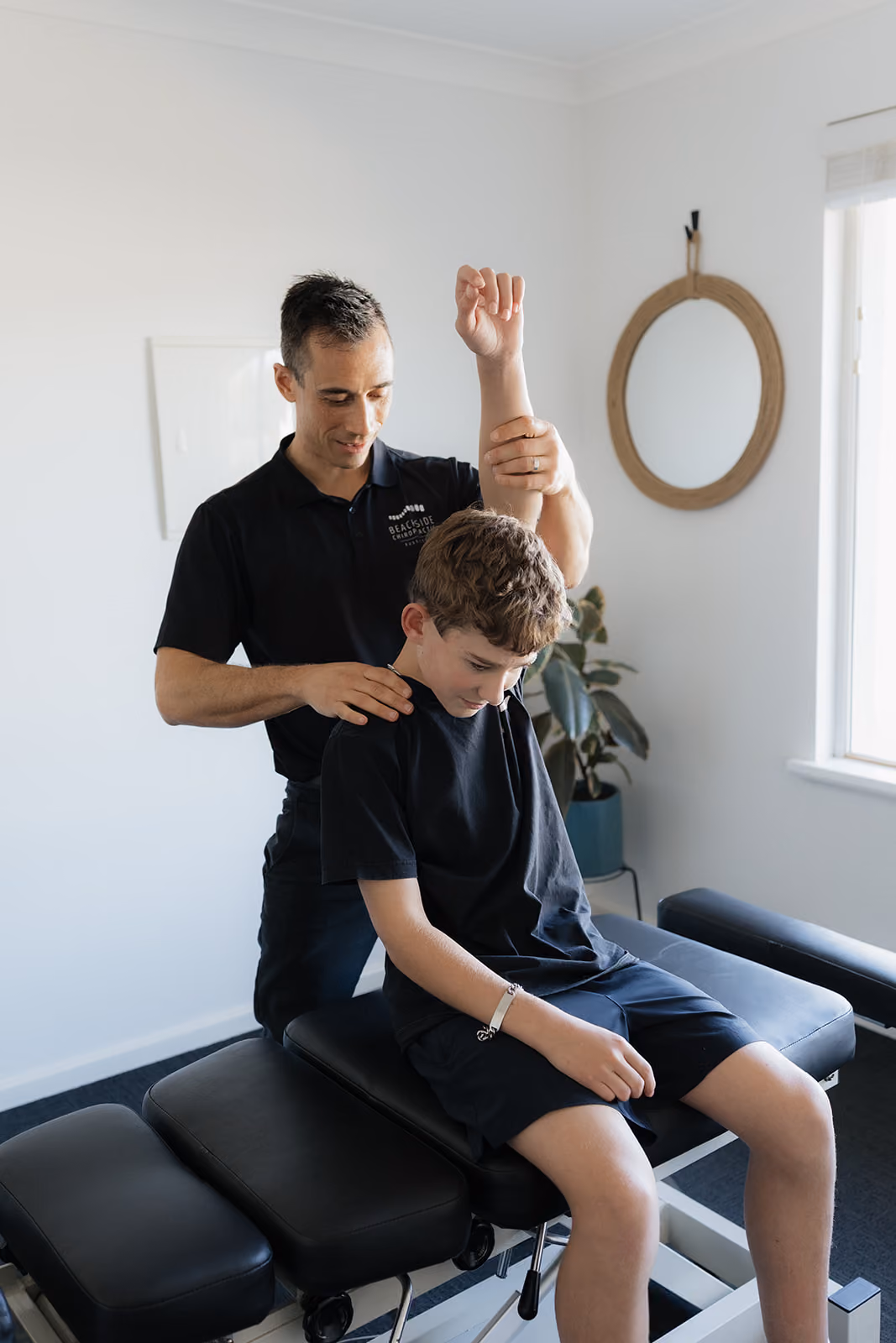 Chiropractor checking a young boy's shoulder mobility at Beachside Chiropractic Busselton