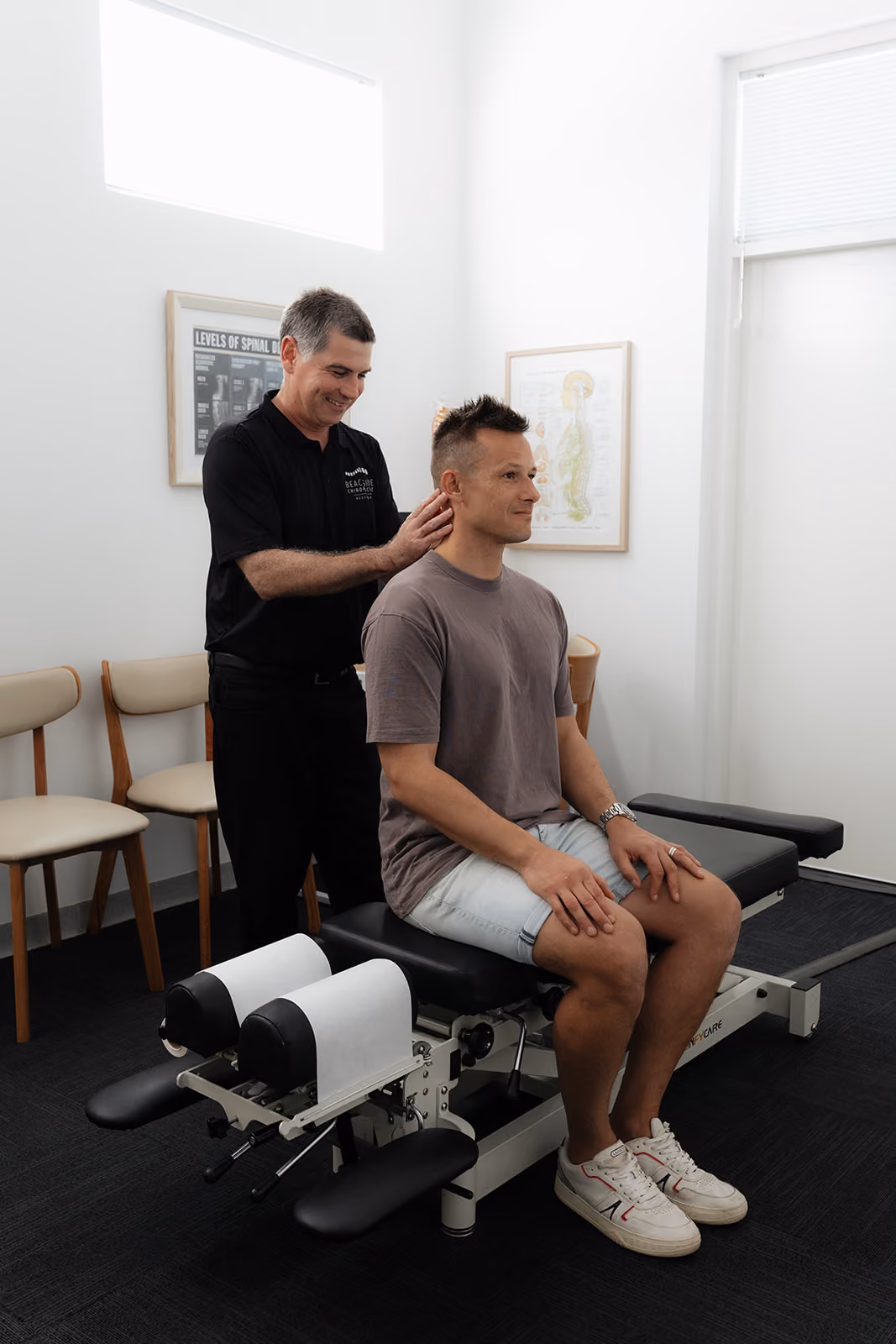 Chiropractor assessing an adult patient's neck and shoulders in the Busselton clinic