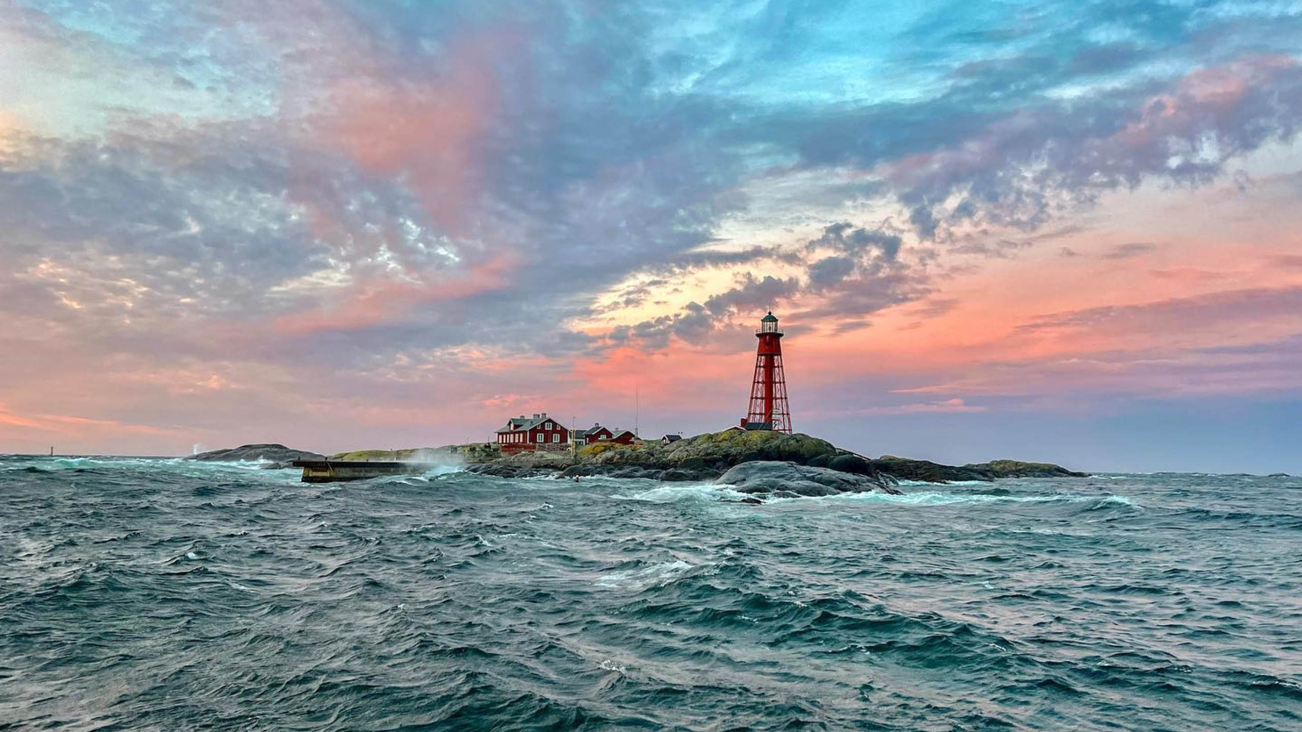 a lighthouse on an island in the sea with pink sky