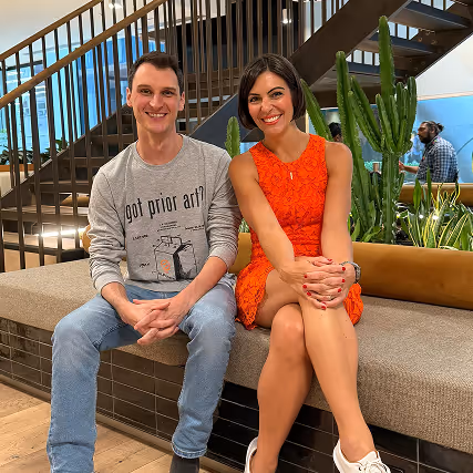 Stephanie Curcio and James Stonehill sitting on a bench together in an office setting