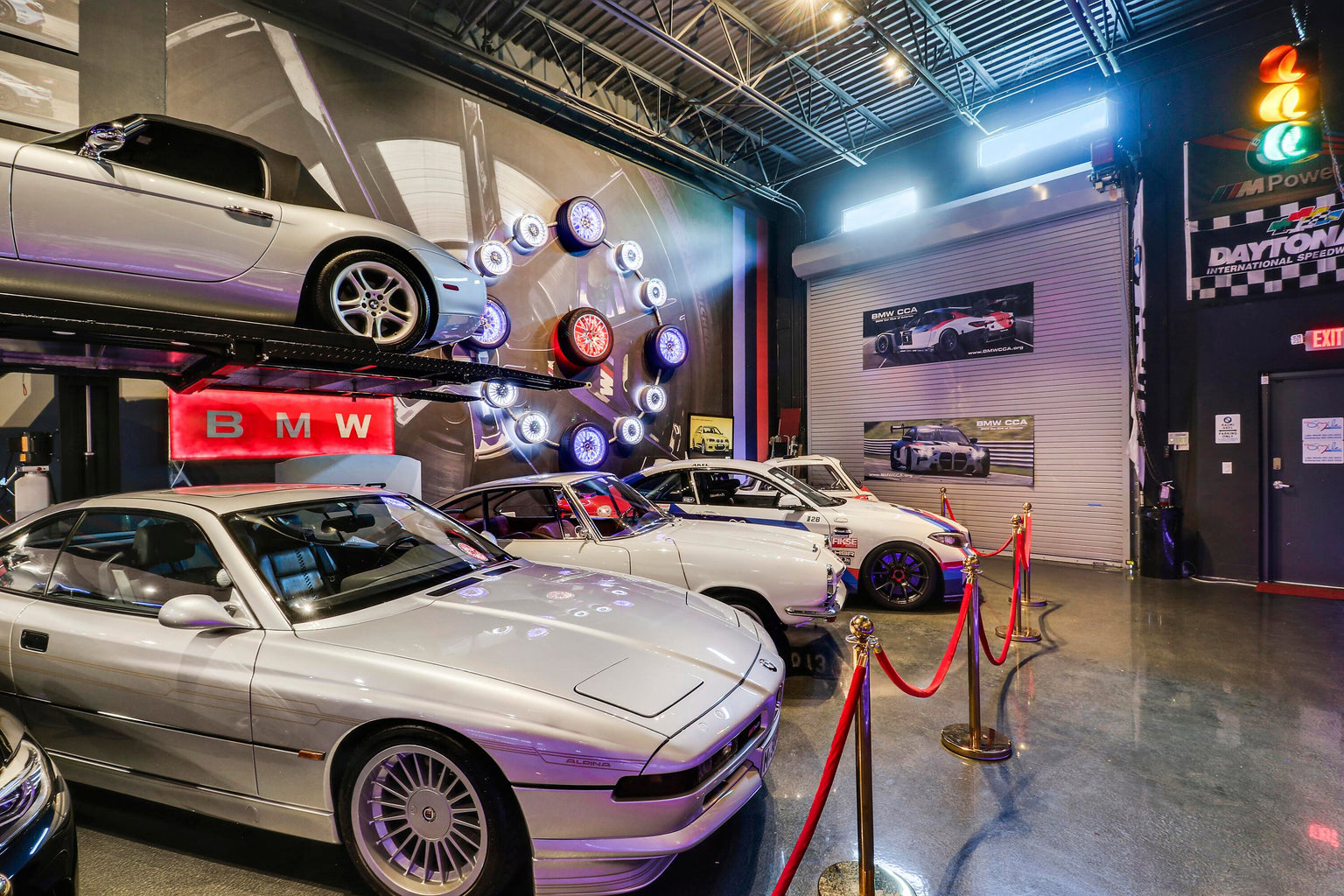 Row of modern commercial garage units with rolling doors numbered 8, 9, and 10, and two parked cars in front.