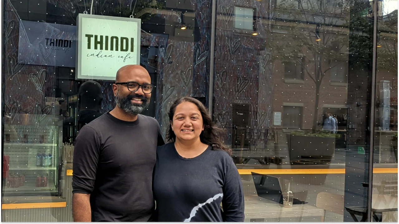 A man and woman standing in front of their cafe