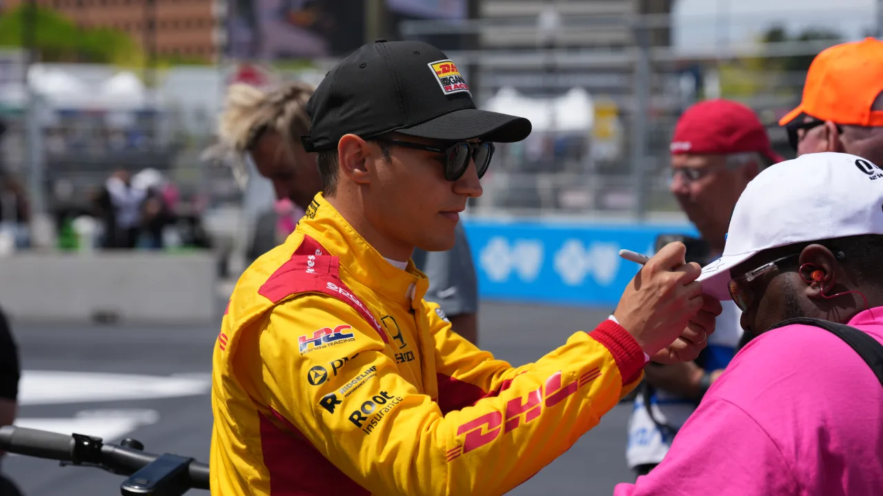 Alex Palou signing a fan's hat at an IndyCar race