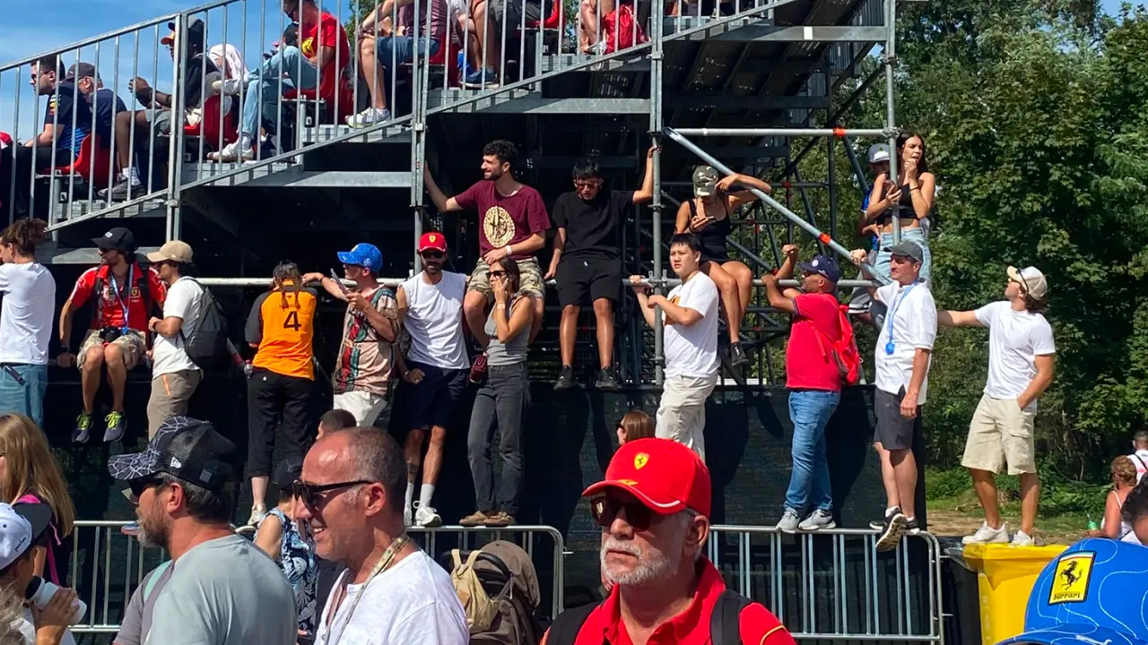 GA fans standing on metal fences for a better view of the track