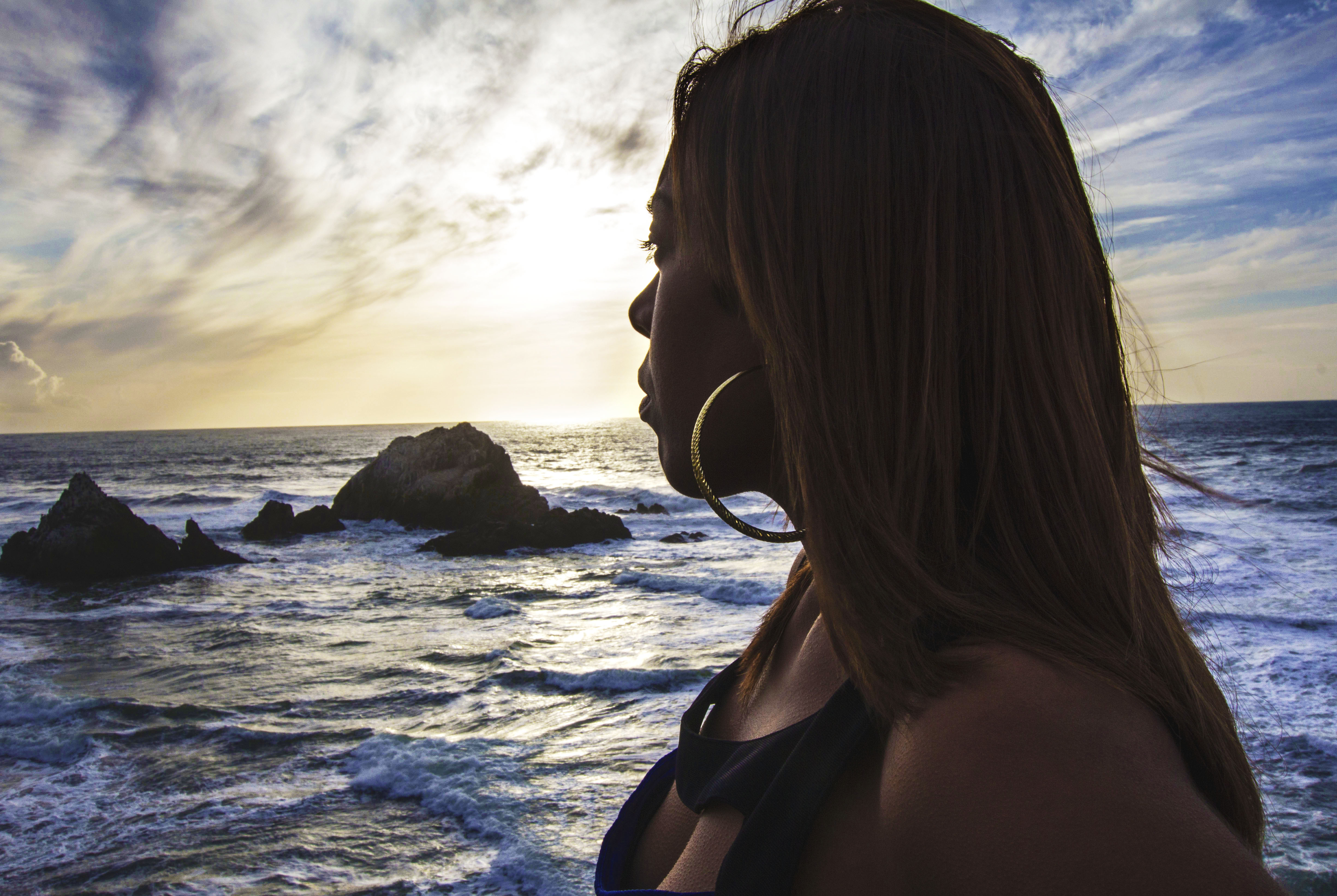 Beautiful woman looking over the edge of land toward the ocean