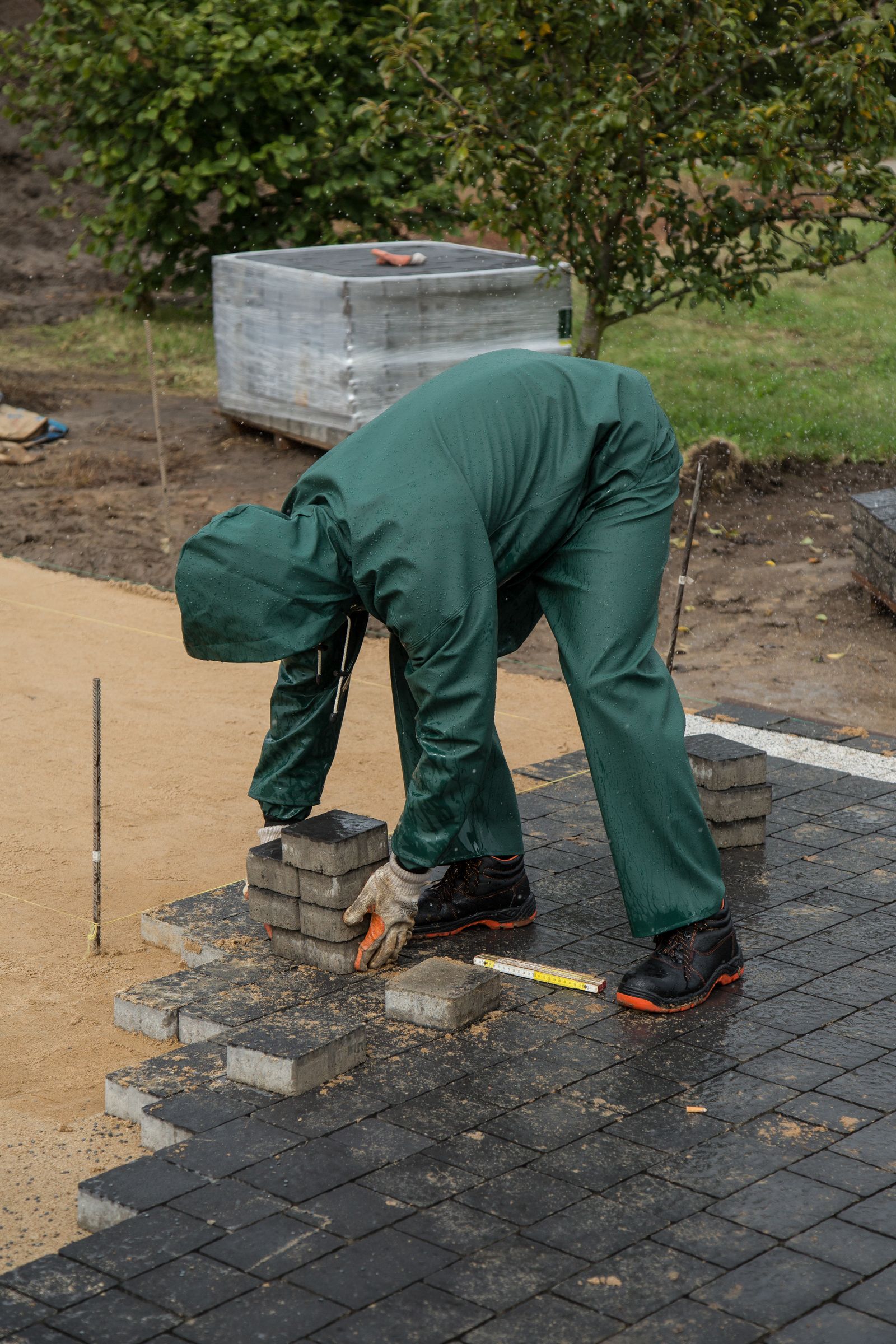 Worker setting brick pavers on a patio base