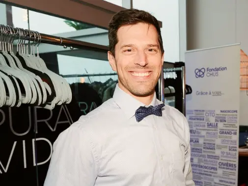Homme souriant portant nœud papillon devant une bannière de la Fondation CHUS.