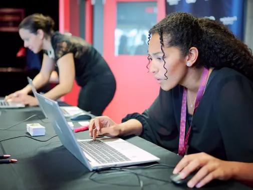 Deux femmes concentrées travaillant sur des ordinateurs portables à une table.
