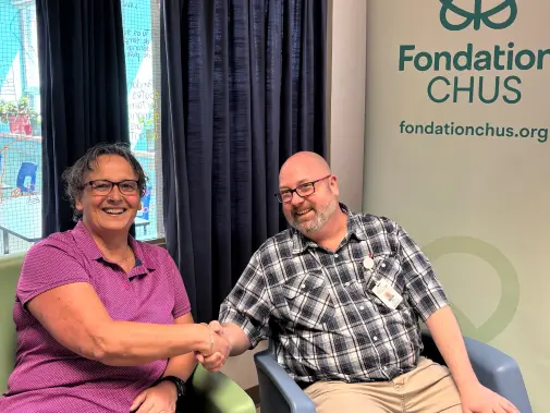 Deux personnes se serrant la main devant une bannière de la Fondation CHUS.