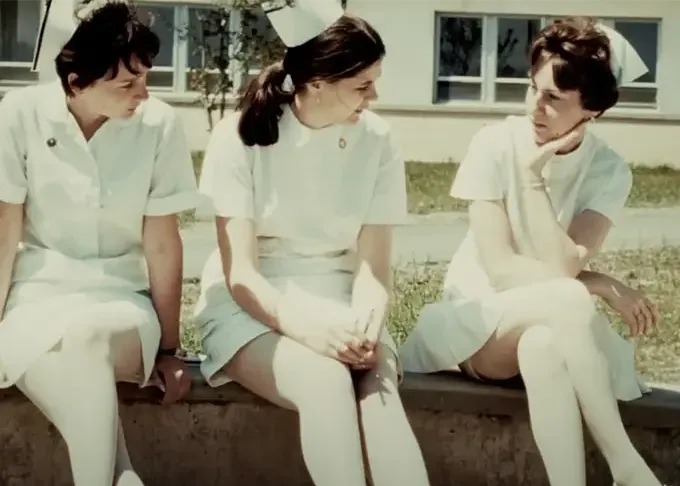 Trois infirmières en uniforme blanc discutant ensemble à l’extérieur de l’hôpital.