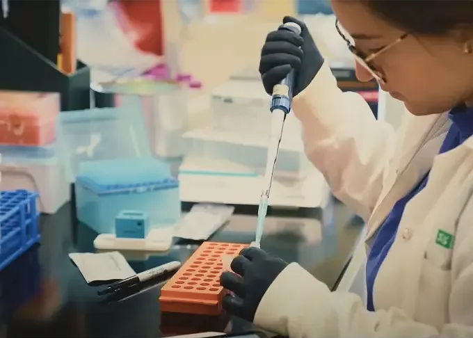 Scientifique manipulant une pipette et des échantillons dans un laboratoire moderne.