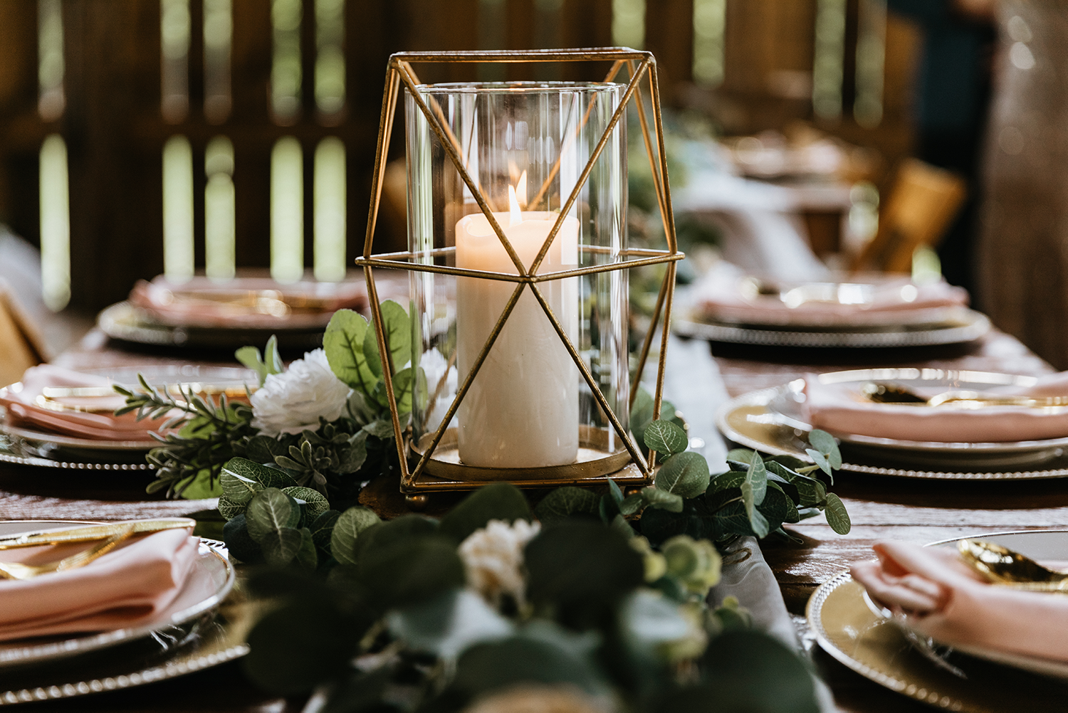 Reception table set with greenery garland down the center and gold and glass lantern centerpiece.