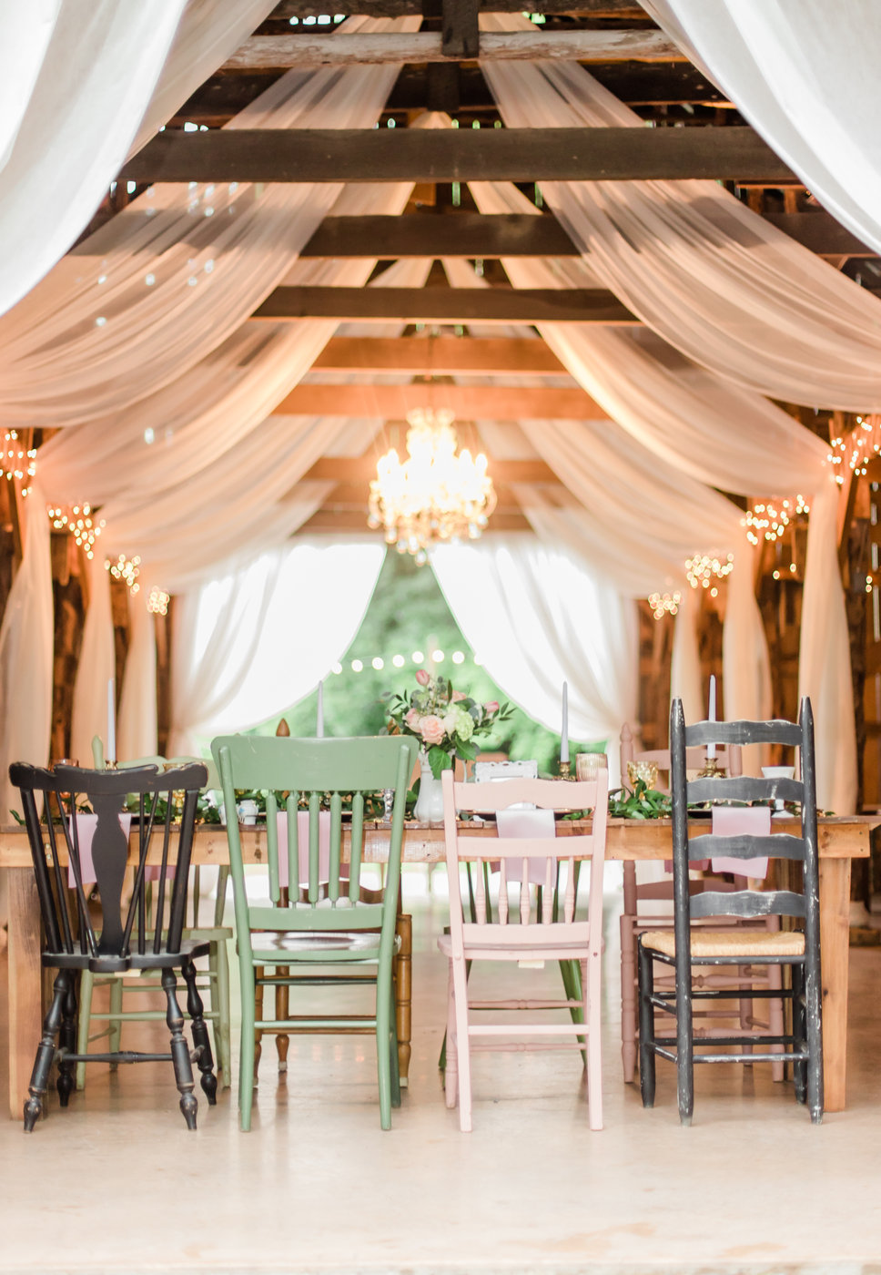 A glimpse inside The Barn at Cedar Grove with a table set with mismatch chairs
