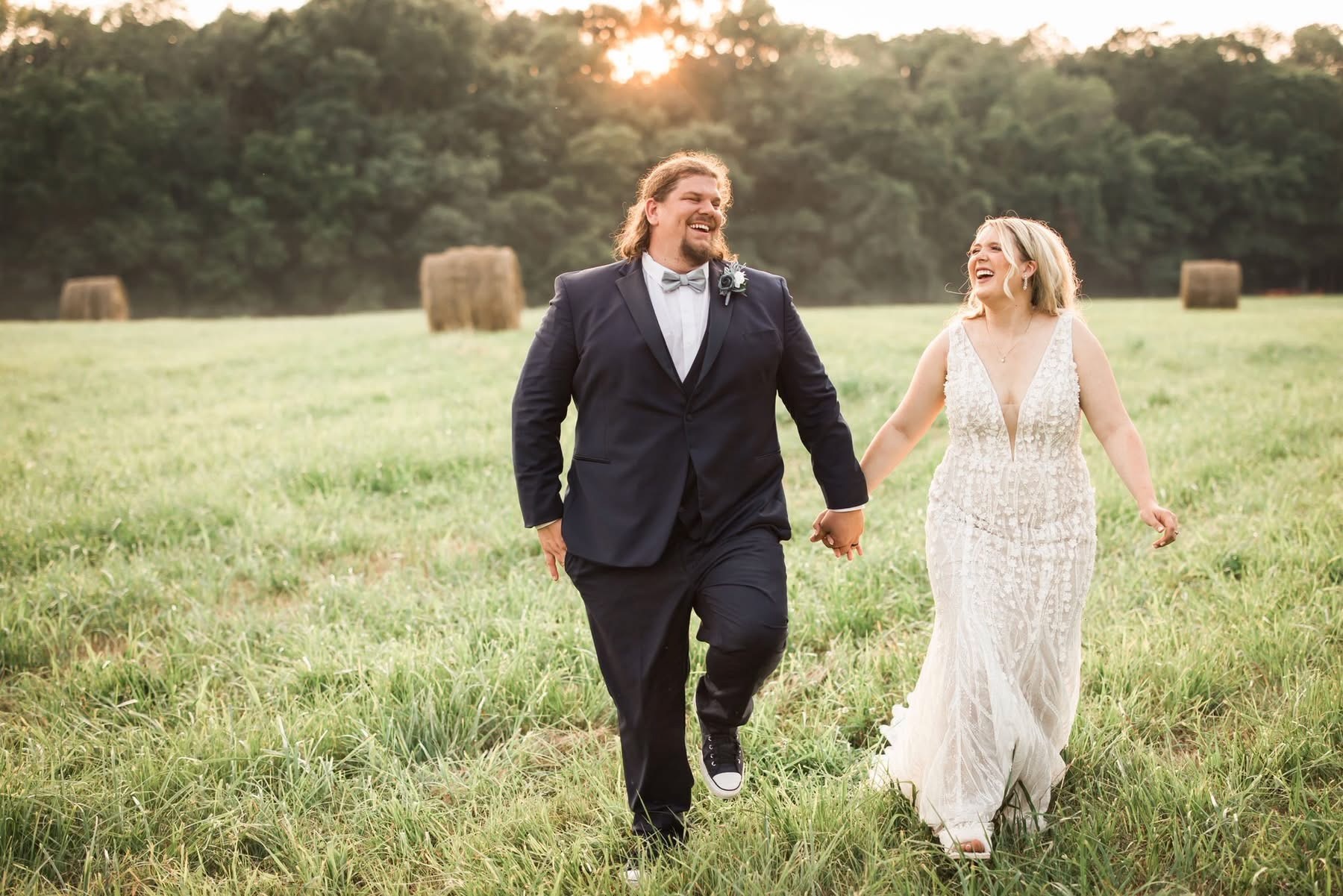 Just married couple walking through the field of freshly baled hay at The Barn at Cedar Grove 
