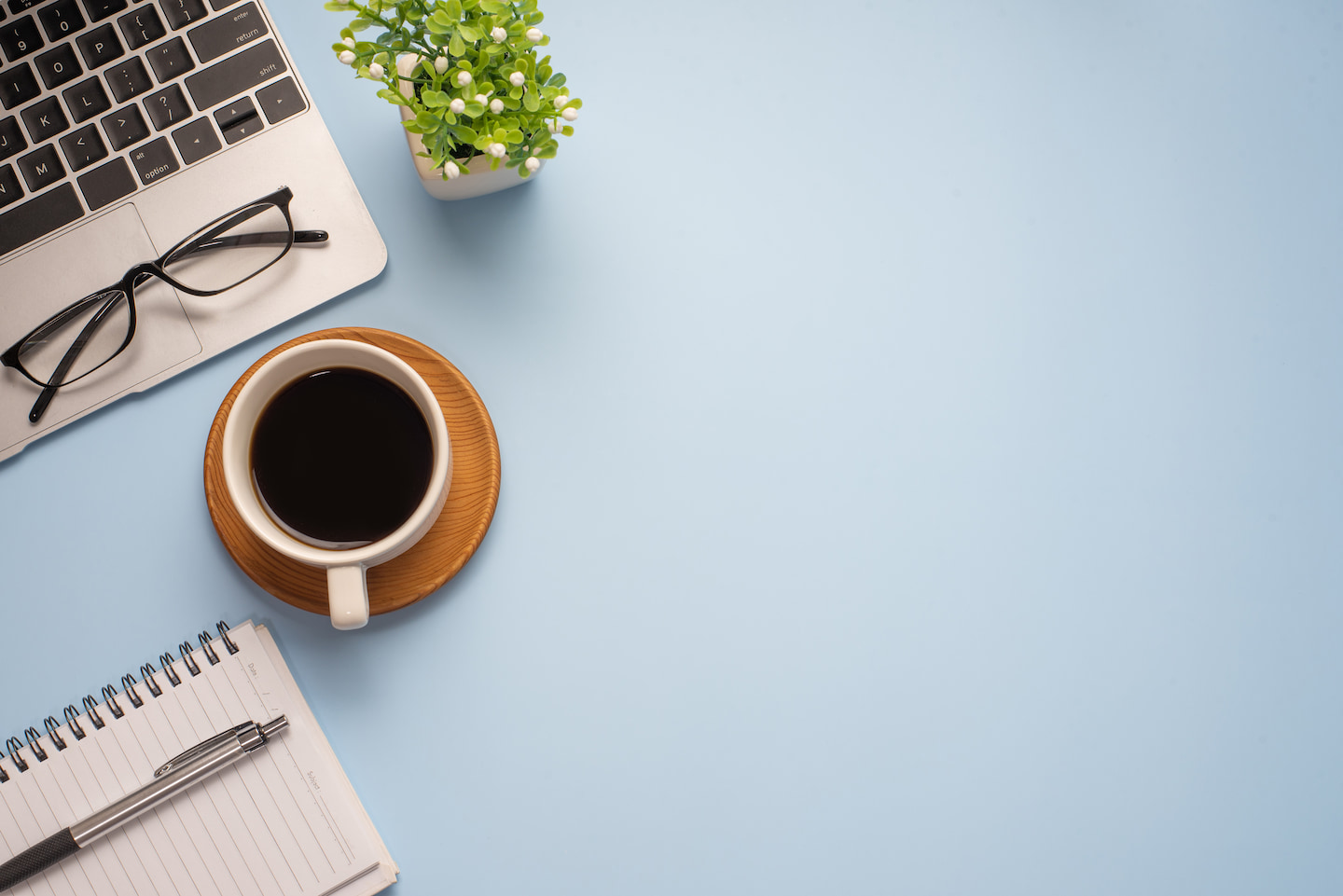Website writing essentials—laptop, notebook, and coffee—sit on a table.